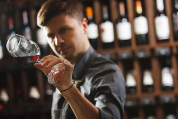 Bokal of red wine on background, male sommelier appreciating drink