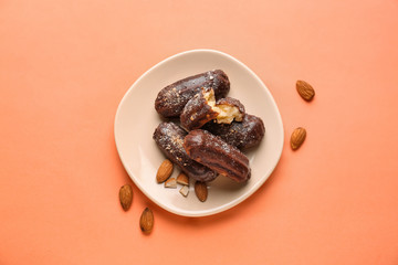 Plate with delicious eclairs on color background, top view