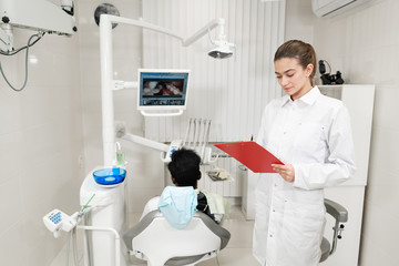 Charming beautiful girl doctor dentist. Young African American male patient at chair at dental clinic. Medicine, health, stomatology concept. dentist conducts inspection and concludes. Woman smiling