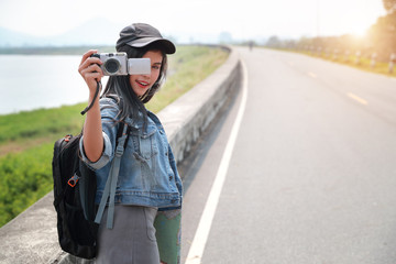 Young asian traveler using camera and taking picture while traveling on holiday vacation