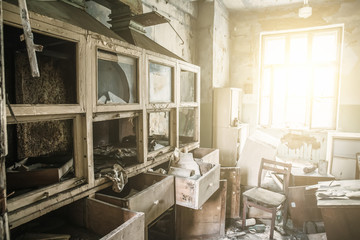 Abandoned and ruined laboratory room with broken furniture and cabinet, bright light from window