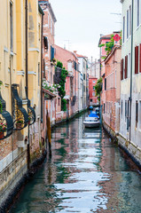 Narrow water canal street with parked boats in Venice Italy