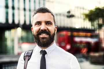 A portrait of hipster businessman standing on the street in London.