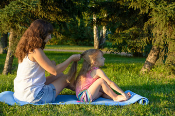 happy mother and daughter sit in the city park at summer