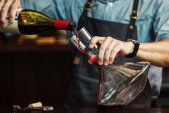 Sommelier pouring red wine into carafe to make perfect color