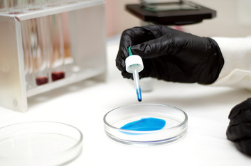  laboratory worker in a white coat working with chemicals under a microscope