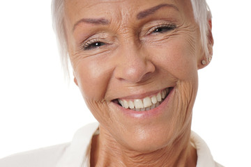 close-up headshot of older woman in her sixties with toothy smile