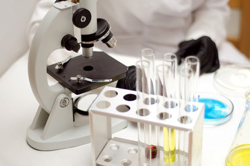 .laboratory equipment, test tubes with colored liquids, Petri dish of microorganisms on white...