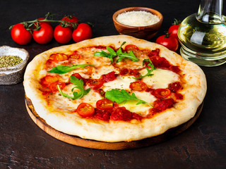 hot homemade Italian pizza margherita with mozzarella and tomatoes on dark brown stone table, side...