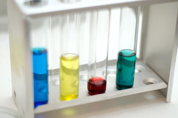 .laboratory equipment, test tubes with colored liquids, Petri dish of microorganisms on white background