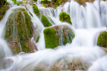 Silky waterfall streams surrounded by mossy rocks and forest plants in Plitvice Lakes National Park, Croatia