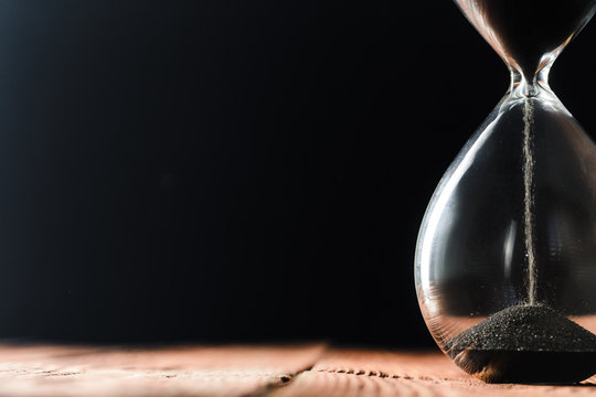 Modern hourglass on wooden background