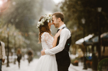 Happy bride and groom after wedding ceremony embracing in rain - obrazy, fototapety, plakaty