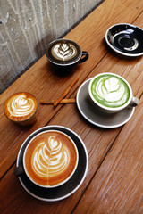 A cup of green tea matcha latte and cup of latte art coffee on wooden background