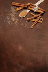Composition with sweet cinnamon sugar on brown background. Vertical photography. Free space for text, recipe