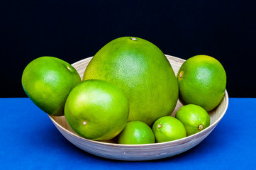 Plate with green citruses fruits. Limes, pomelo, grapefruits.