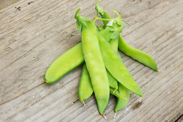 Pods of green peas on the background of old wood. The concept of vegetarianism and healthy eating. Copy space.