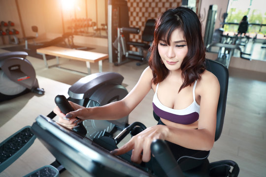 portrait of young healthy and sporty woman using exercise machine in gym (this image for fitness and workout concept)