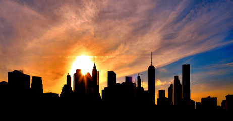 Obraz na płótnie Canvas warm sunset on manhattan modern architecture skyline with moody sky and silhouettes of skyscrapers, Manhattan New York city