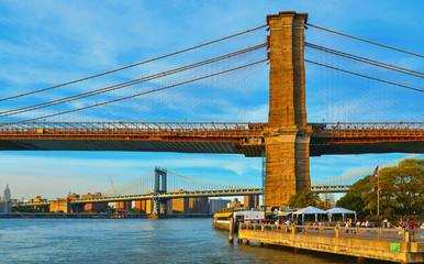 Brooklyn promenade with famous Brooklyn bride and Manhattan bridge and river hudson in background against cloudy colorful blue sky in New York, USA