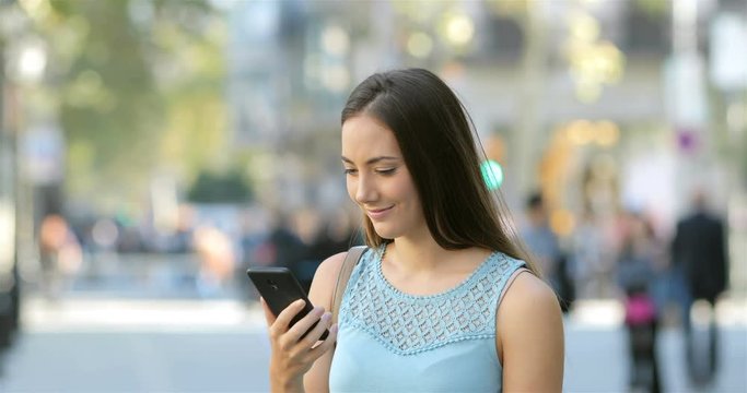 Excited woman reading online good news in a smart phone in the street