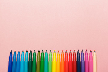 Assortment of colorful felt tip pens on pastel pink background