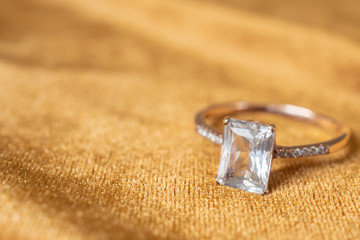 Jewelry diamond ring on golden fabric background close up