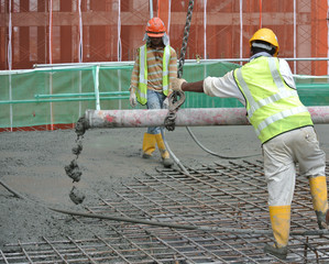 Construction workers are doing the concreting work using hose from the elephant crane or concrete...