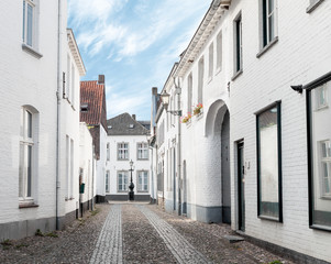 Fototapeta na wymiar Empty old town street with white painted buildings early in the morning in Thorn, Netherlands 