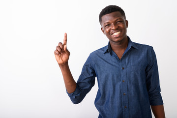 Studio shot of young happy black African man smiling while point