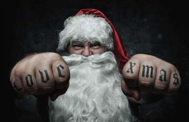 Funny mad Santa Claus showing fists with tattoos