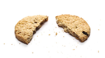 Round cracked wholewheat biscuit, cookie with raisins and crumbs isolated on white background