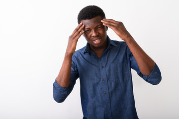 Studio shot of young black African man looking stressed while ha