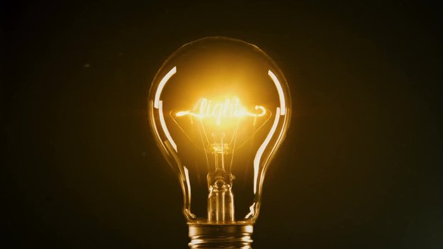 Light bulb on dark background with fog. Conceptual image. The word JESUS can be read on the filament