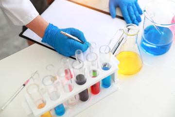 scientist woman with equipment and laboratory glassware holding chemical liquid and checking result using as science research background