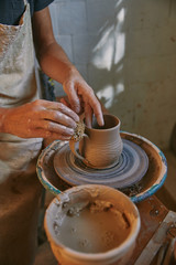 Fototapeta na wymiar cropped image of potter working on pottery wheel at workshop