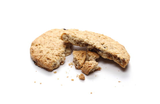 Round cracked wholewheat biscuit, cookie with raisins and crumbs isolated on white background