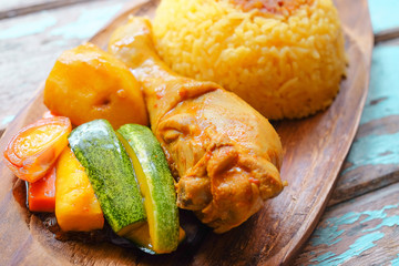 Top view of Malay traditional food called 'Nasi Minyak' with colorful rice, red chili ,spicy sauce, chicken, cucumber, carrot, and potato on the wooden plate.