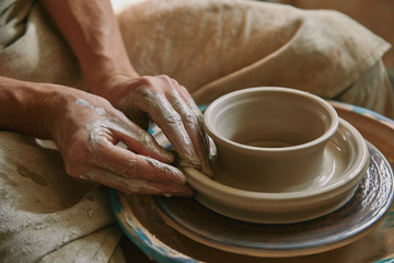 Close up view of professional potter working on pottery wheel at workshop