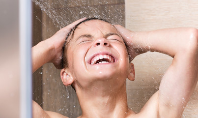 Cheerful boy washing face and body in shower in the bathroom - 230597822