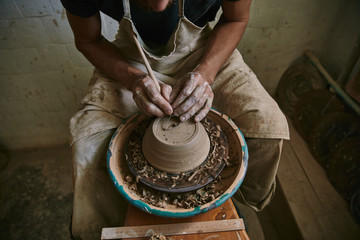 Fototapeta na wymiar cropped image of professional potter decorating clay pot at workshop
