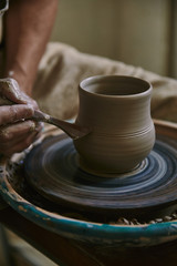 Fototapeta na wymiar close up view of professional potter decorating clay pot at workshop