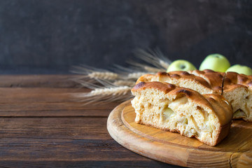 Round home-made apple pie, cobbler, brown Betty, Apple Charlotte on wooden background with apples and spikelets.