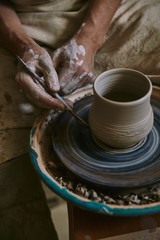 Fototapeta na wymiar partial view of professional potter decorating clay pot at workshop