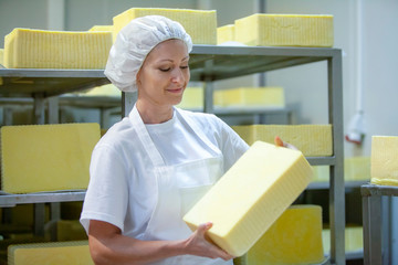 Female worker on yellow cheese production line in an industrial factory