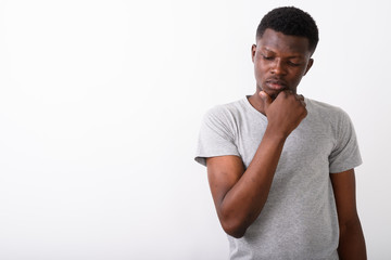 Studio shot of young black African man thinking while looking sa