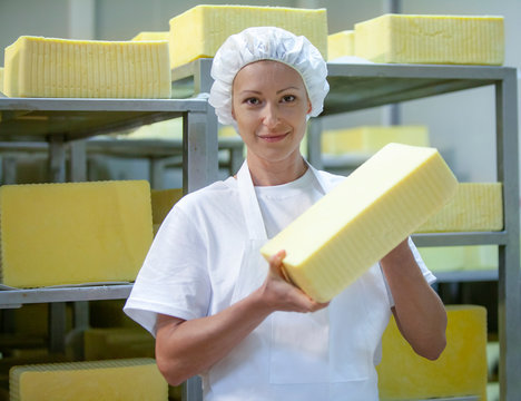 Female worker on yellow cheese production line in an industrial factory