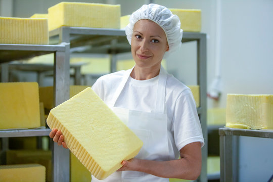 Female worker on yellow cheese production line in an industrial factory