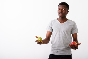 Studio shot of young black African man holding red apple and gre