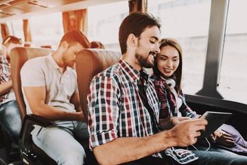 Smiling Couple Using Digital Tablet in Tour Bus